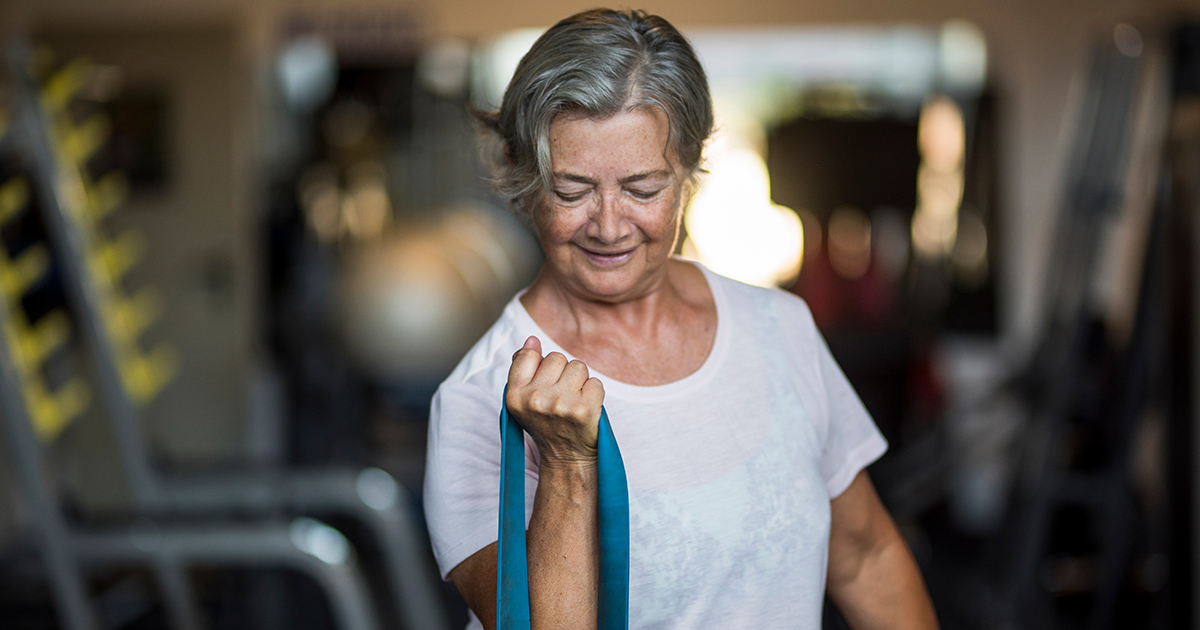 kvinna som förebygger osteoporors genom fysisk aktivitet med band