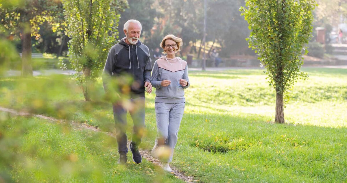Äldre par joggar på en stig